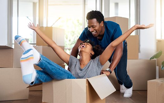 Full length shot of an affectionate young couple playing with a box while moving into their new home